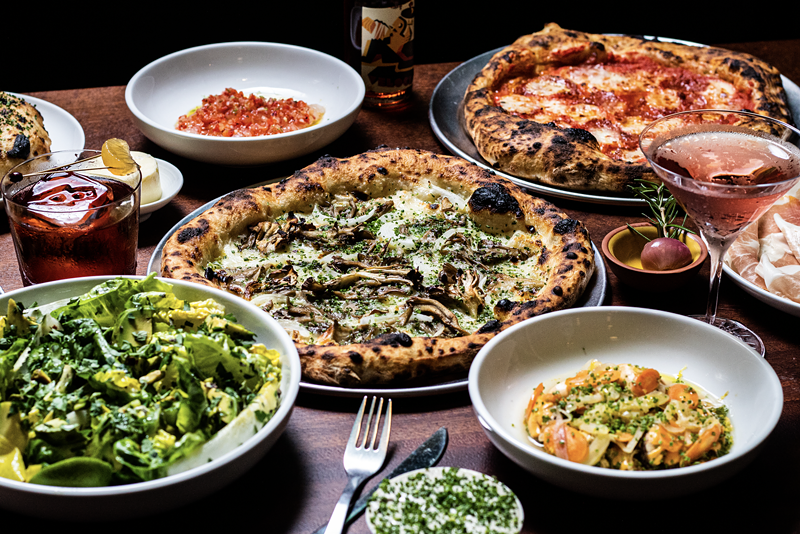 Image: an array of dishes and pizzas on a wood table