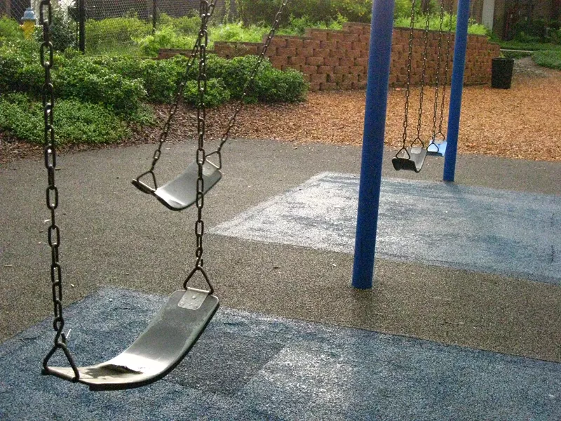 Image: an empty swingset on a playground