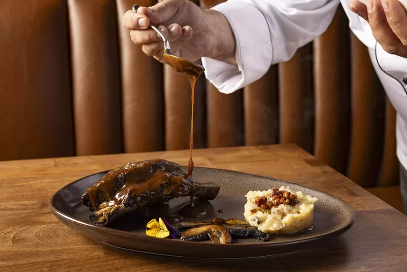 Image: A chef pours sauce on steak