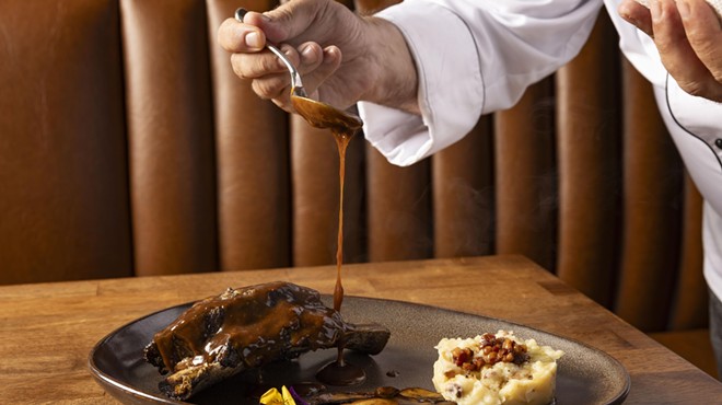 A chef pours sauce on steak