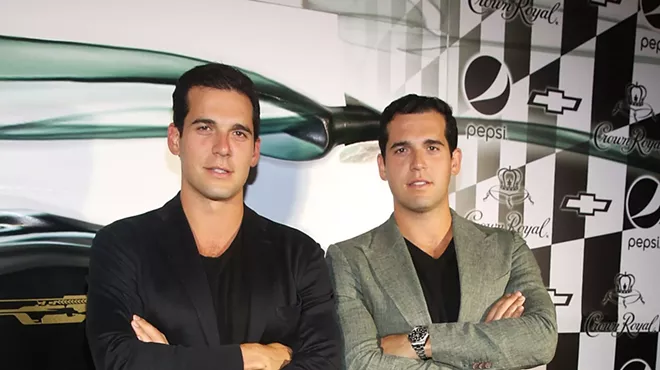 Twin brothers Alon and Oren Alexander stand with arms crossed while posing for photo at an event