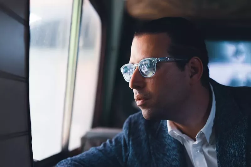 Image: Alfredo Rodriguez, wearing sunglasses, looks out of a window