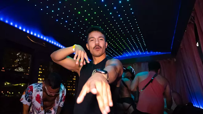 a man poses for the camera inside a neon-lit party bus