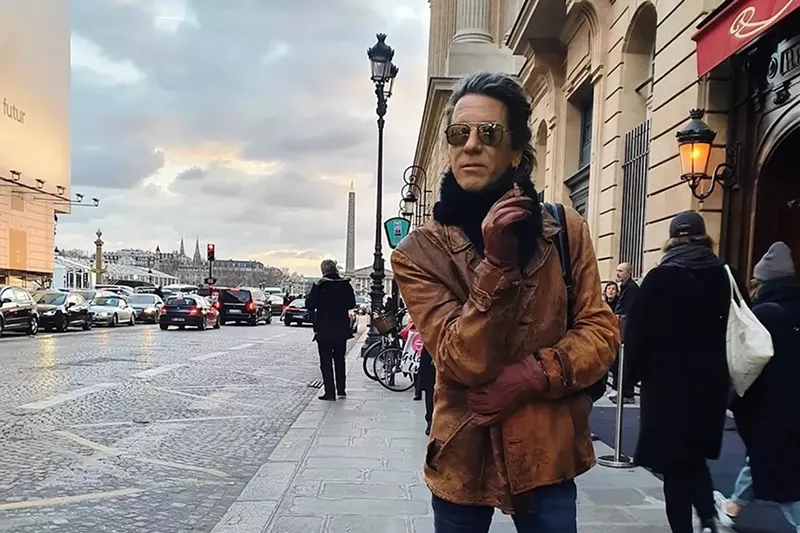 Image: Composer William Basinski standing on the sidewalk smoking a cigarette