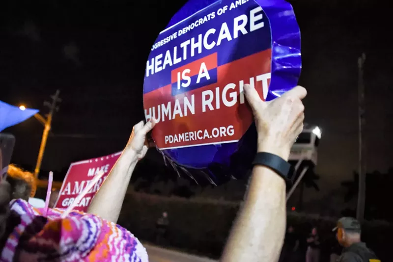 Image: A protester holds a sign outside Mar-a-Lago February 4.