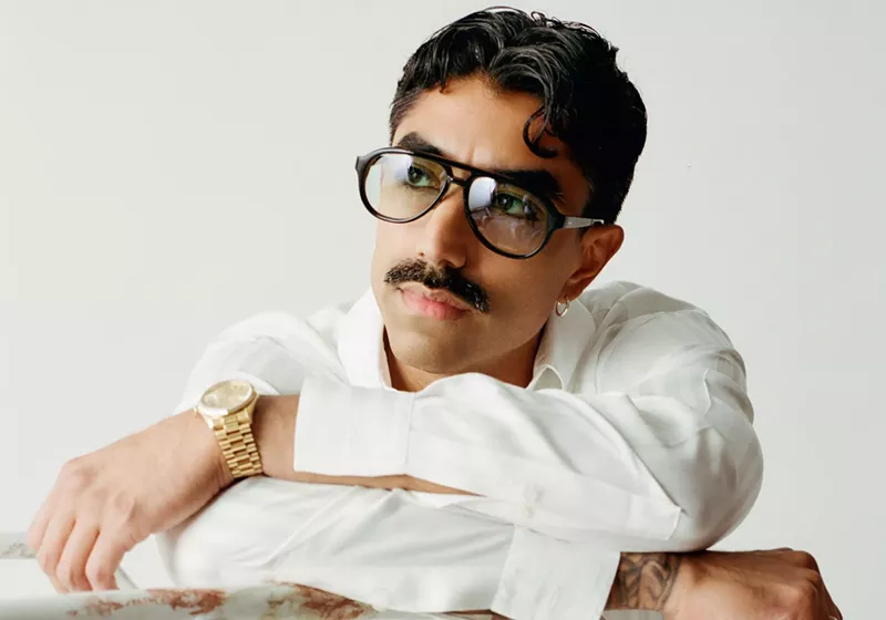 Image: Portrait of a man wearing glasses and white clothing.