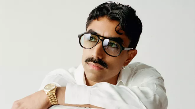 Portrait of a man wearing glasses and white clothing.