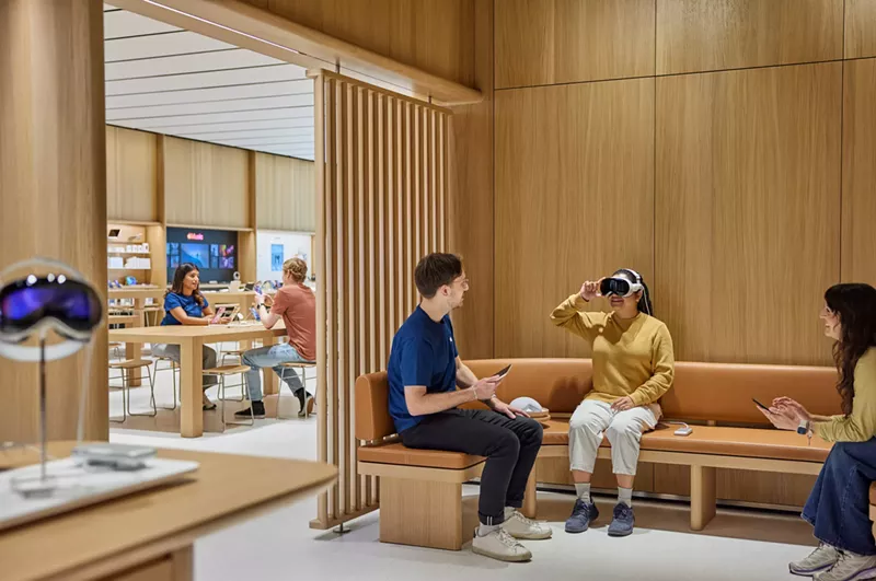Image: A store employee assists a woman trying out a virtual reality headset