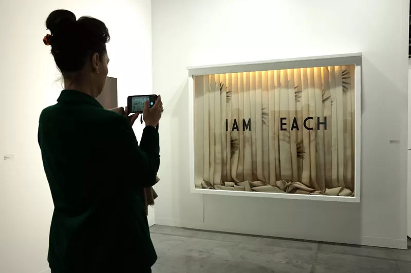 Image: Woman snapping a photo of an artwork at Art Basel Miami Beach 2024