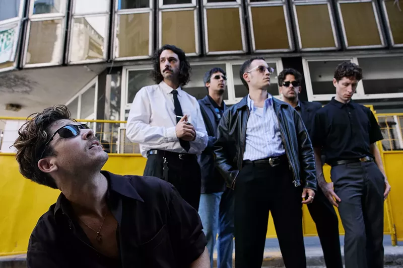 Image: Image of a five-piece band posing in front of a building.