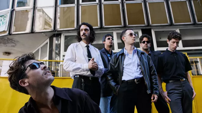 Image of a five-piece band posing in front of a building.