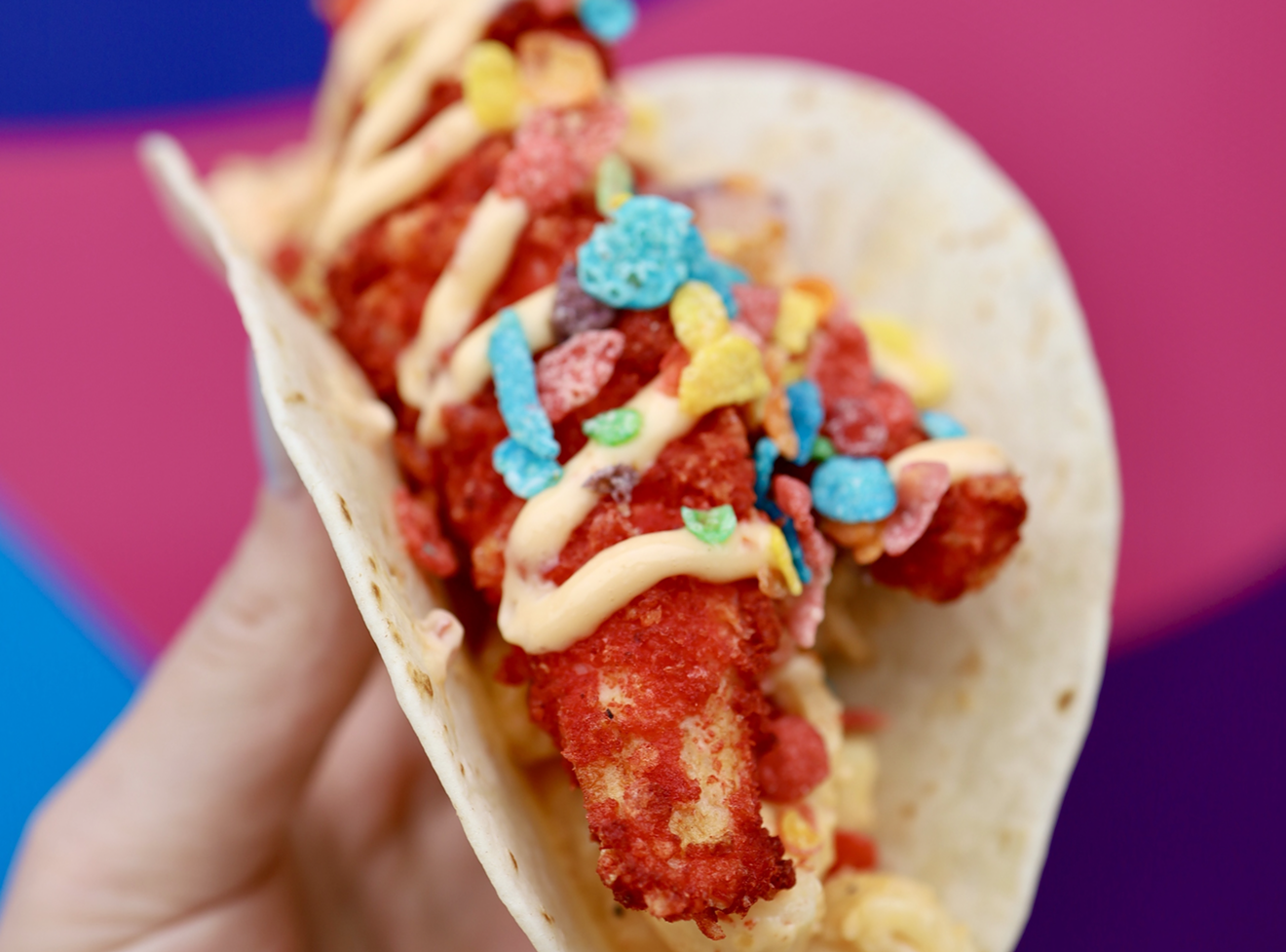 The "4/20 Blazin' Taco" from Velvet Taco is made of mac & cheese, Flamin' Hot Cheetos-covered chicken tenders, and red chili aioli sprinkled with Fruity Pebbles cereal.
