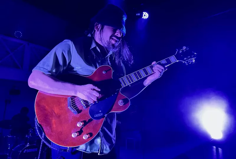 Image: A guitarist playing a red Gretsch
