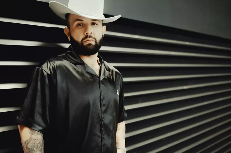 Image: Carin León in a black shirt and white cowboy hat