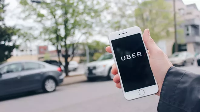 a hand holds up a phone with the Uber app on the screen