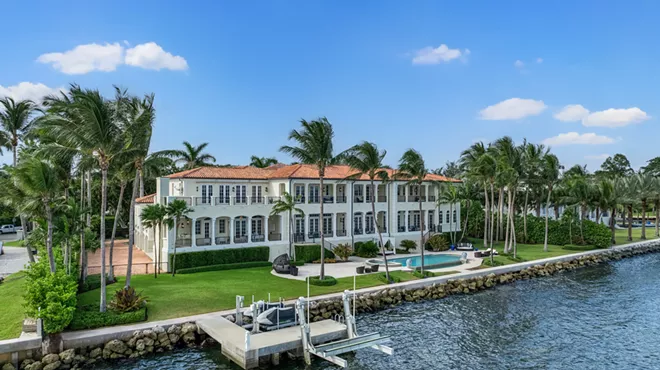 Backyard view of large cream waterfront mansion