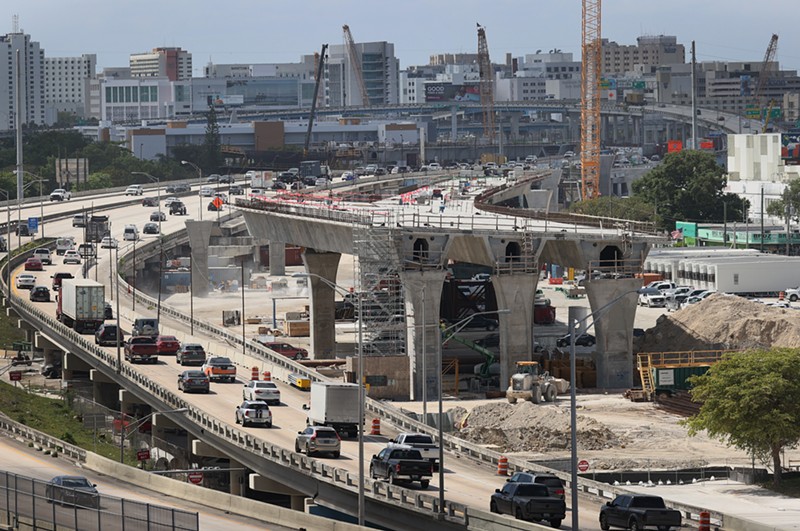 Construction workers build the “Signature Bridge,” replacing and improving a busy highway intersection at I-95 and I-395 on March 17, 2021, in downtown Miami.