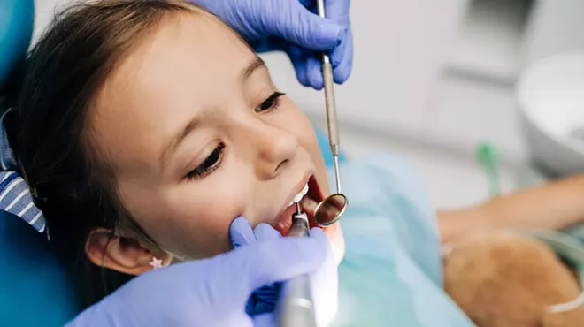 Cute little girl sitting in a dental chair and receiving dental treatment.