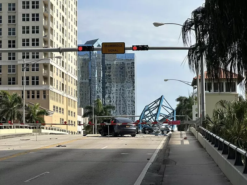 Image: A broken off piece of a crane sits atop a vehicle in the middle of a Florida bridge after a construction accident