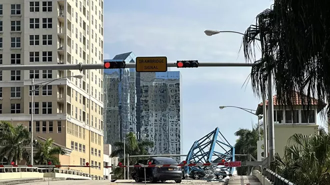 A broken off piece of a crane sits atop a vehicle in the middle of a Florida bridge after a construction accident
