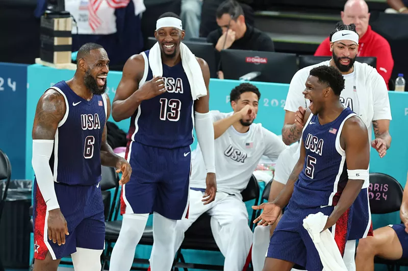Image: Lebron James, Anthony Edwards, and Bam Adebayo on the court, laughing and smiling near the sideline during a 2024 Olympics matchup