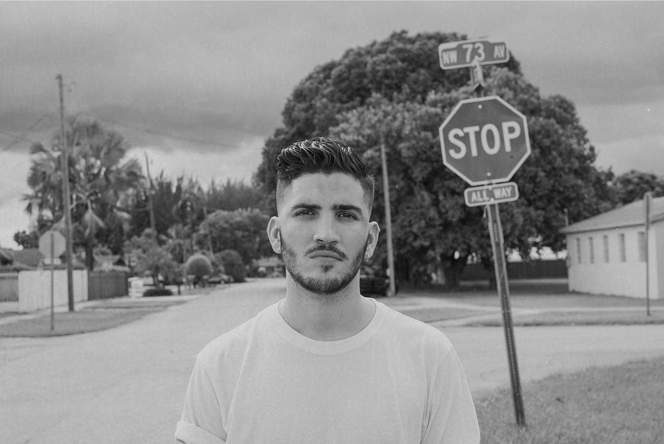 Danny poses in front of a stop sign in his childhood neighborhood, the one place he truly considers home.