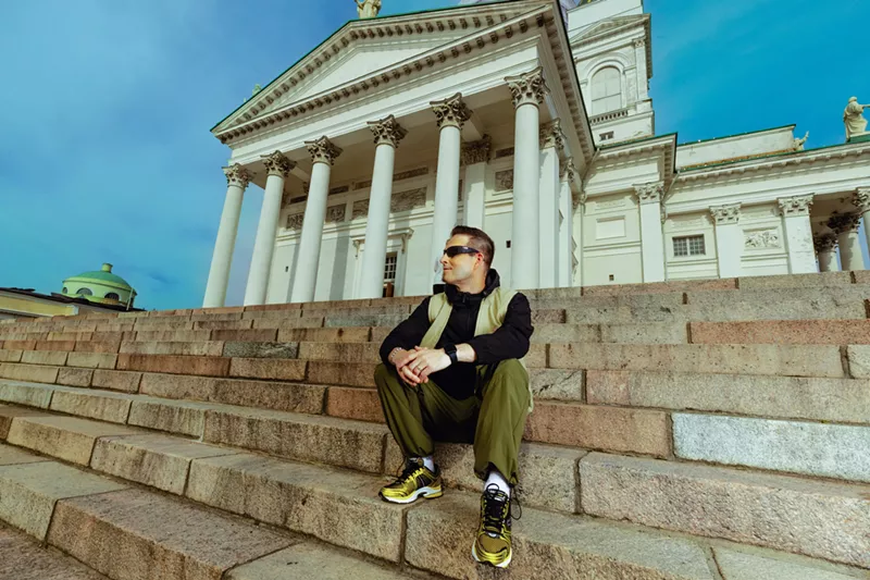 Image: A man sitting on a stair in front of a church.