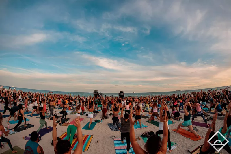 Image: A large group of people doing yoga on the beach at dawn