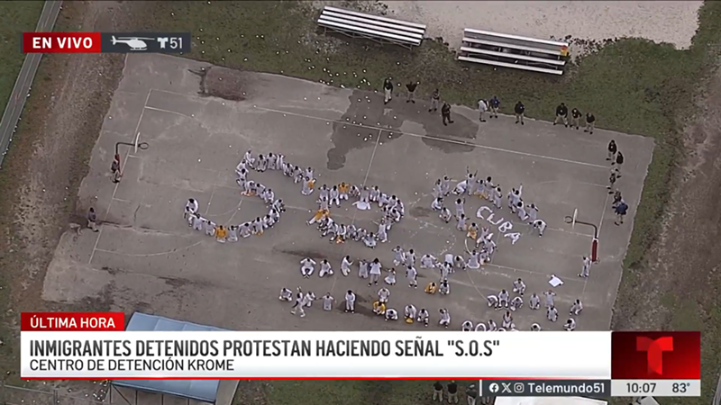 Image: On Thursday morning, a Telemundo news helicopter flew overhead the facility and captured the scene of dozens of men wearing mostly white jumpsuits standing outside the detention center and forming the letters S-O-S.