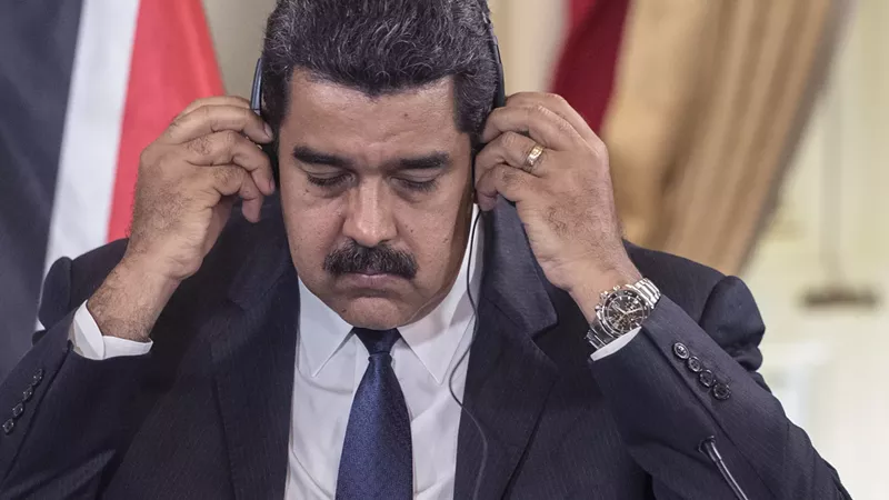 Image: Nicolás Maduro listens to a headset in 2016.