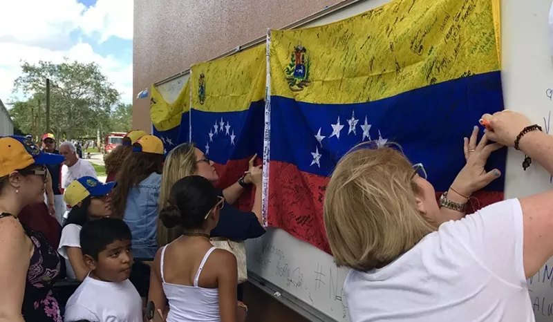 Image: Women signing Venezuelan flags at a demonstration.