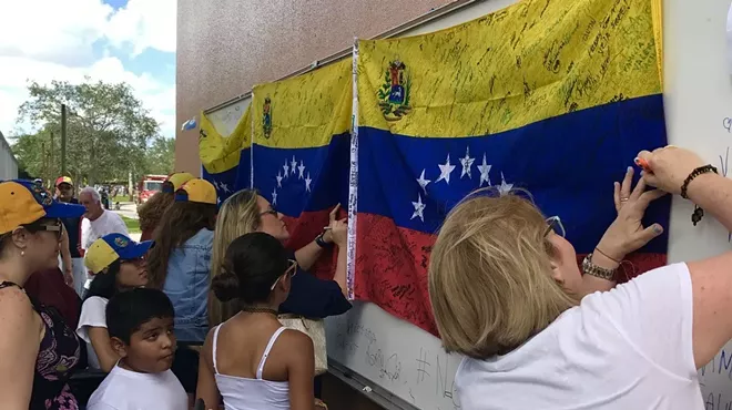 Women signing Venezuelan flags at a demonstration.