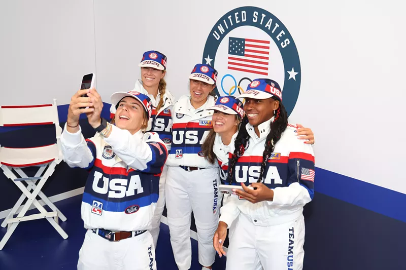 Image: Five U.S. Olympians decked out in Olympic gear, smiling and huddled together in Paris