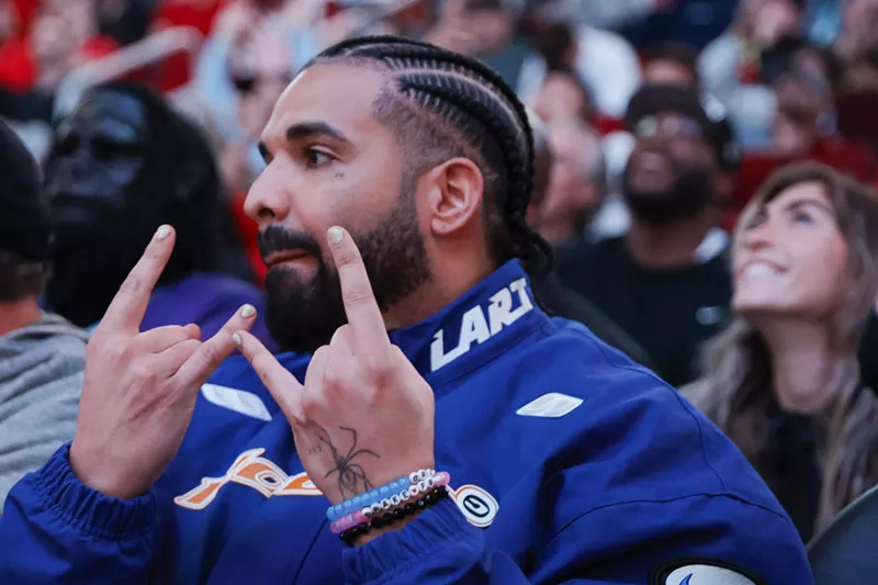 Image: Closeup of rapper Drake throwing up hand signs at a Houston Rockets game.