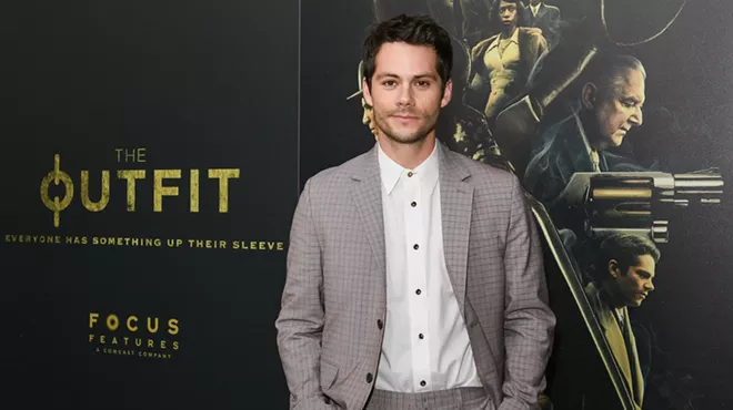 Actor Dylan O'Brien wears a suit on a red carpet at a film premiere.