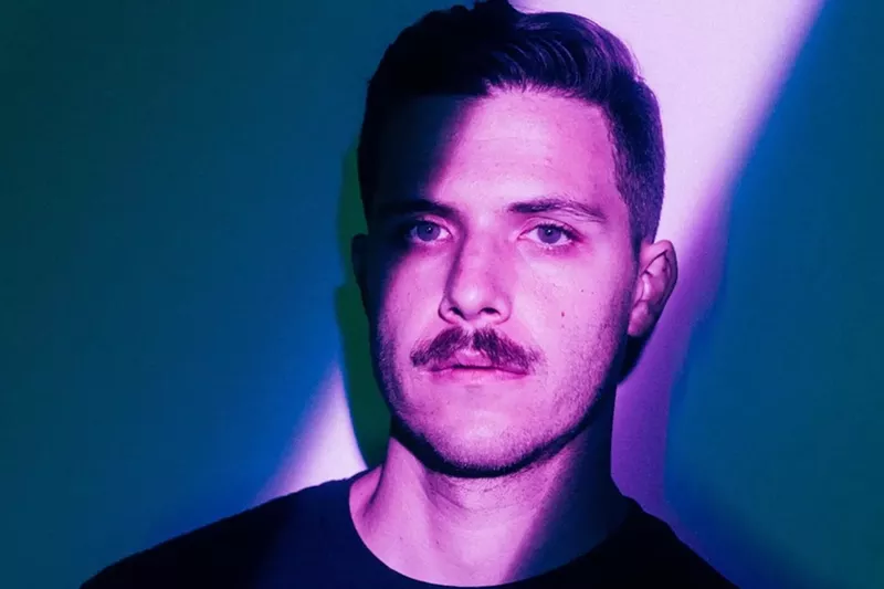 Image: DJ and producer Enamour illuminated with a purple light