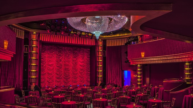 The interior of the Faena Theater with a red velvet curtain and huge crystal chandelier