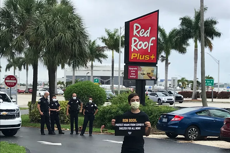 Image: A member of the Dream Defenders protests outside of a Red Roof Plus hotel.