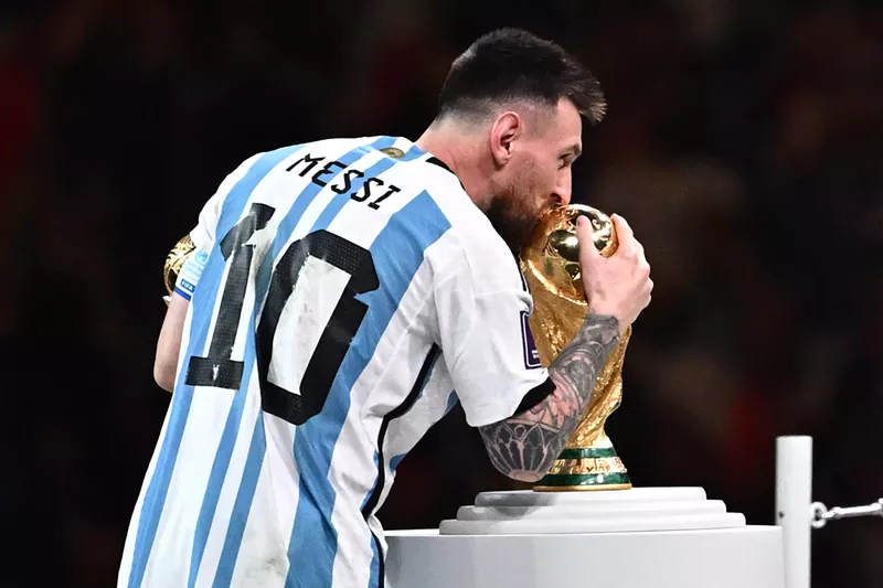 Image: Soccer legend Lionel Messi kisses the World Cup trophy.