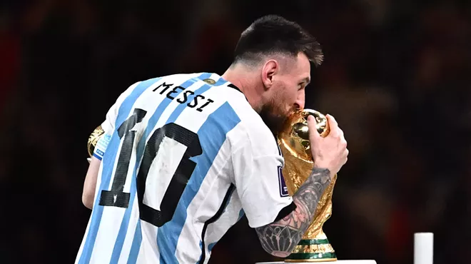 Soccer legend Lionel Messi kisses the World Cup trophy.