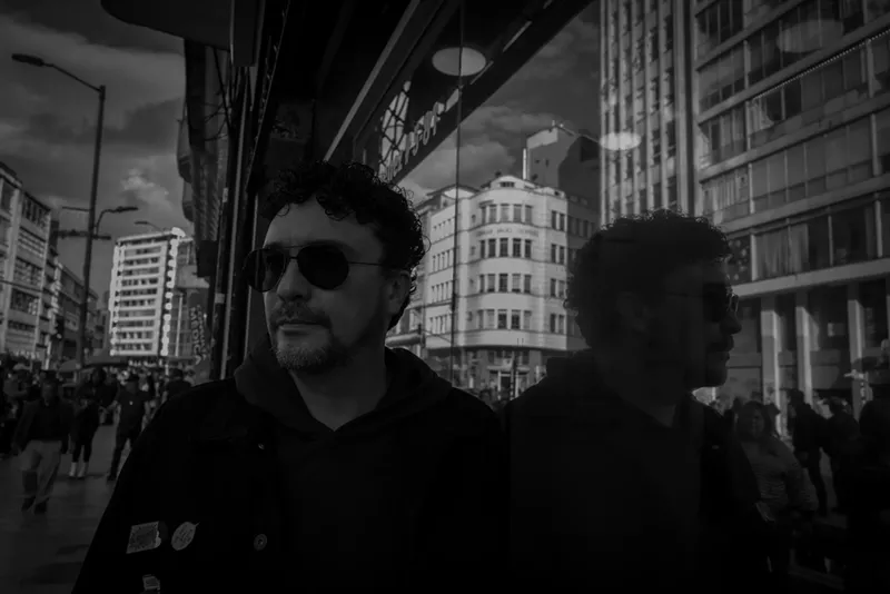 Image: Blck and white portrait of a man wearing glasses, looking nostalgic.