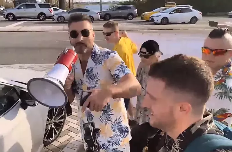 Image: Jon Minadeo holds a megaphone during a neo-Nazi gathering outside the Chabad of South Orlando in February 2023.