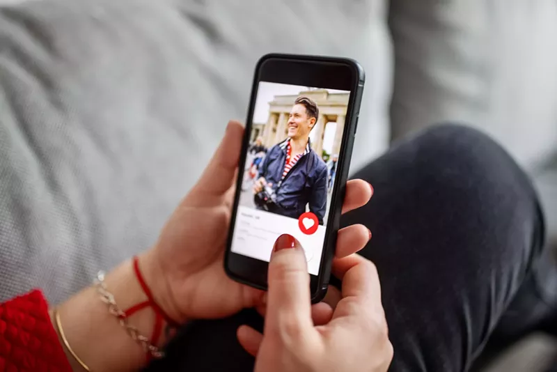 Image: A woman looking at a man's dating profile on her phone
