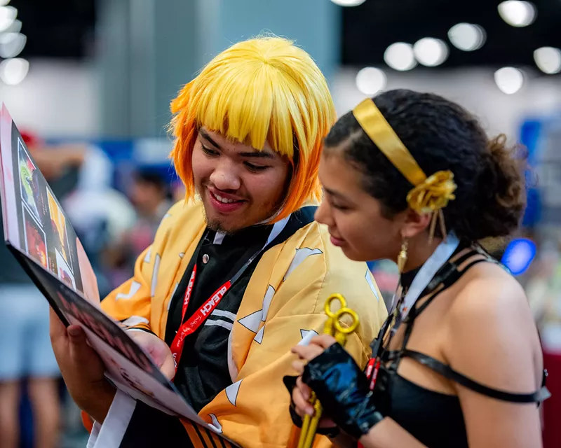 Image: two young people in costume read a graphic novel at a cosplay convention