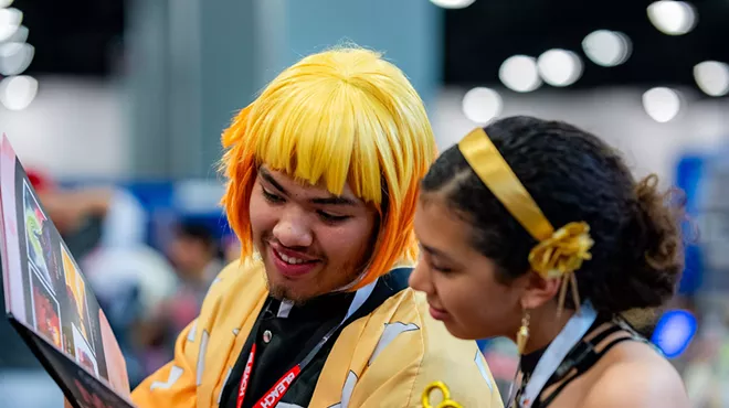 two young people in costume read a graphic novel at a cosplay convention