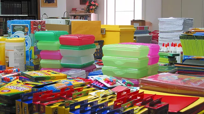 School supplies like crayons and pencil boxes sit on tables.