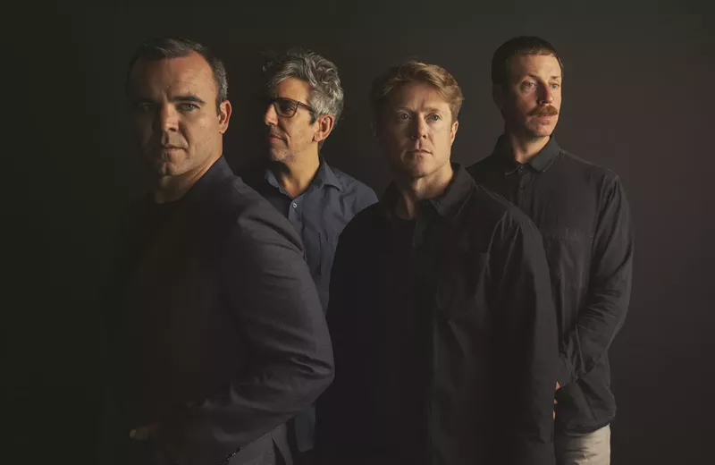 Image: portrait of four band members standing side by side