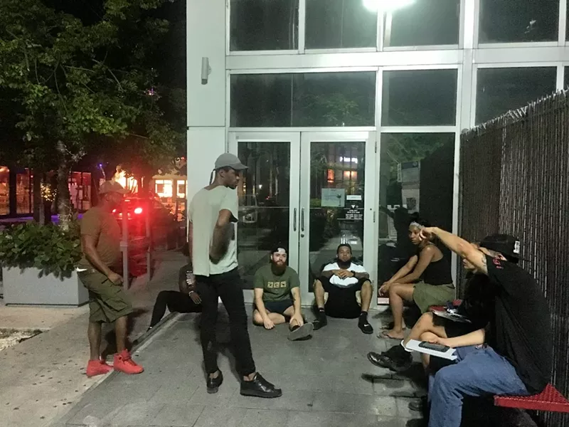 Image: Workers sit outside a shuttered Gigi.