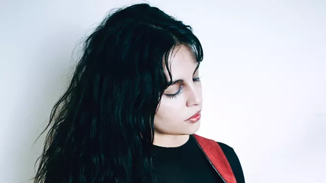 Woman with black hair playing guitar