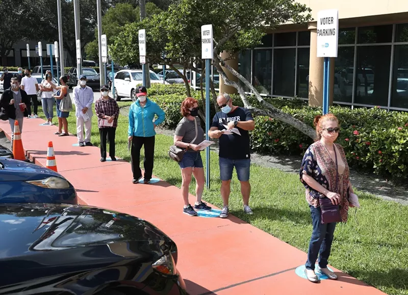 Image: Voters wait in line to drop off their vote-by-mail ballots at Miami-Dade's election headquarters on October 14, 2020.